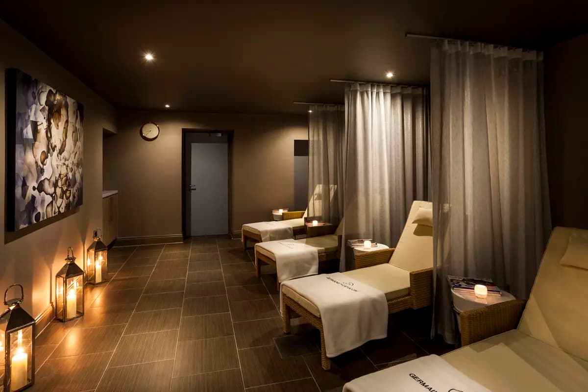 Tranquil thermal relaxation lounge at Daffodil Hotel and Spa Grasmere featuring multiple heated loungers with privacy curtains, ambient candlelit atmosphere, contemporary design with natural wood tones, peaceful adults-only sanctuary in Lake District village setting