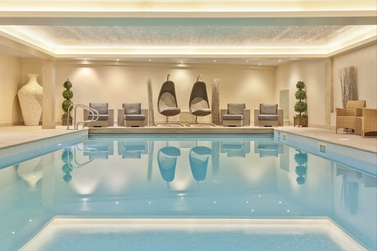 Elegant indoor pool at The Salutation Hotel and Spa in Ambleside featuring starlit fibre optic ceiling, suspended designer pod chairs, modern grey loungers, and sophisticated neutral colour palette creating a tranquil spa experience in the heart of the Lake District