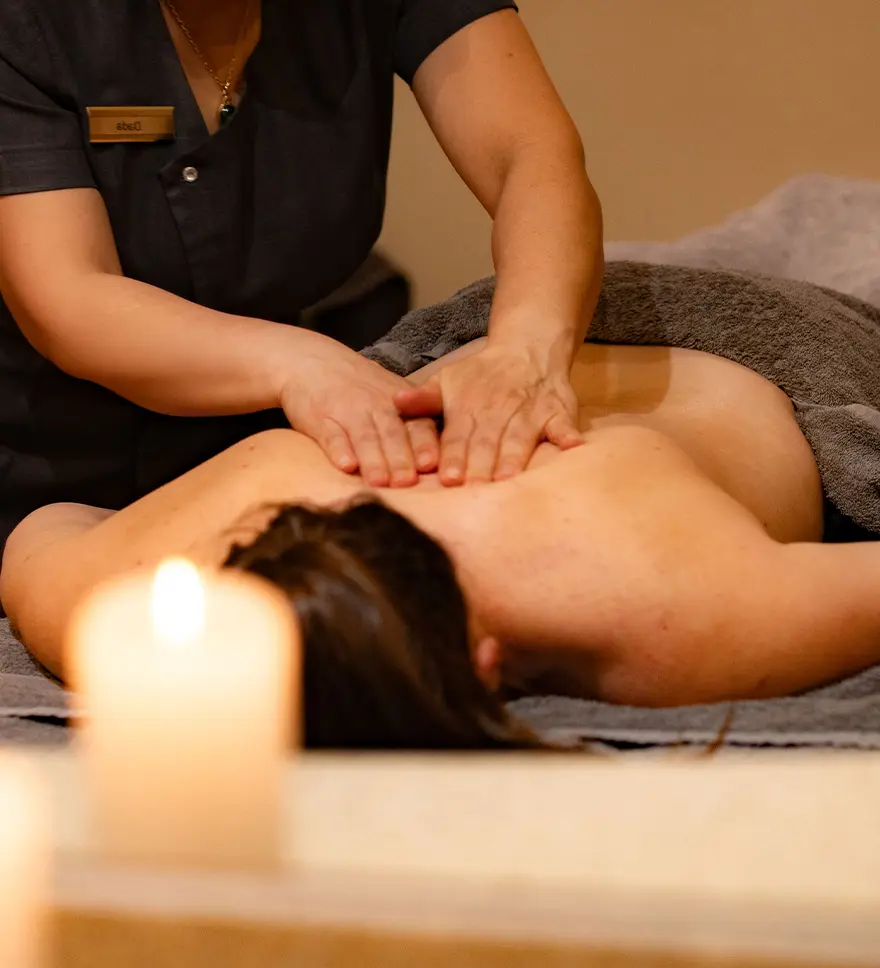 Therapeutic back massage treatment at Lakeside Hotel and Spa in Newby Bridge, professional therapist delivering relaxing spa therapy with soft candlelit ambiance, luxury wellness experience on the southern shores of Lake Windermere in the Lake District Lakeside Hotel & Spa
